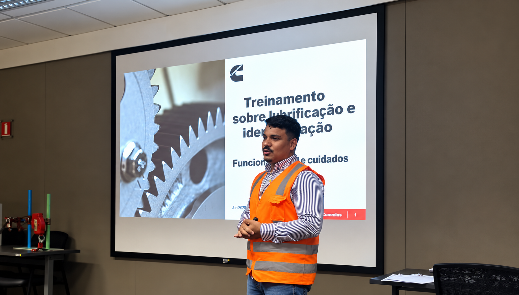 Instrutor com colete laranja durante uma apresentação de treinamento.
